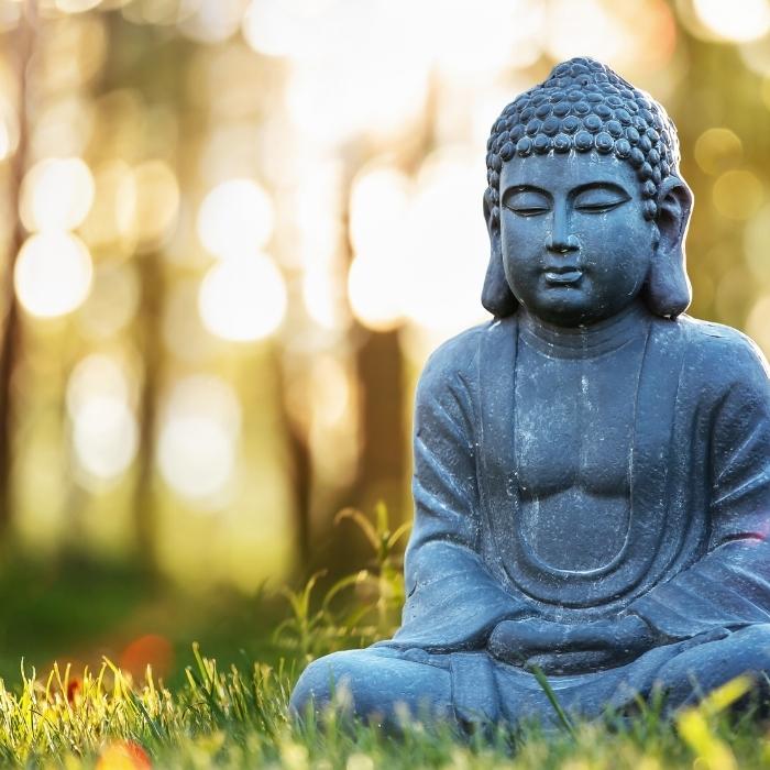 Statue of Buddah meditating in a garden.
