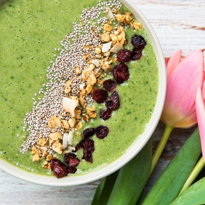 High protein green smoothie in a bowl with nut and seed toppings.