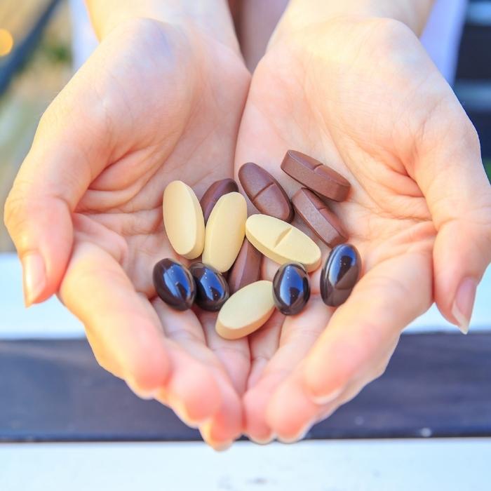 A woman's hands holding various vitamins and supplements.