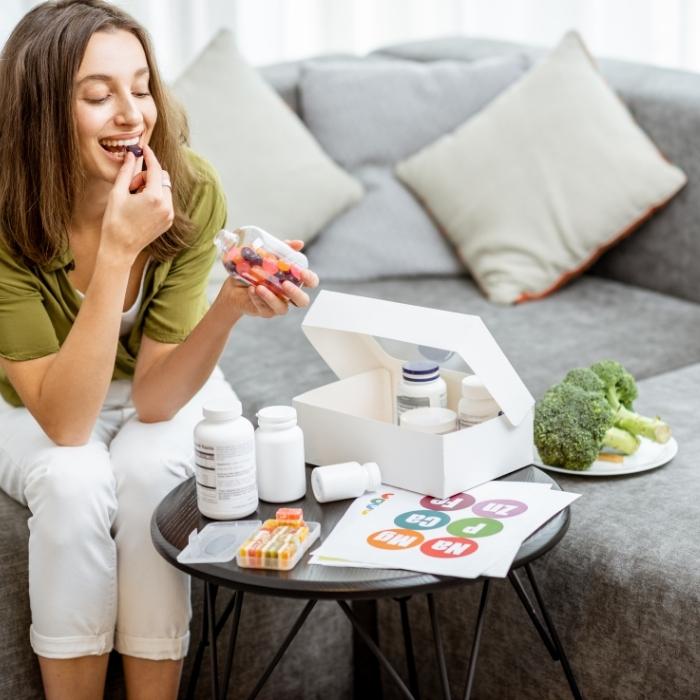 Woman taking lots of multivitamins and supplements while sitting on a couch.