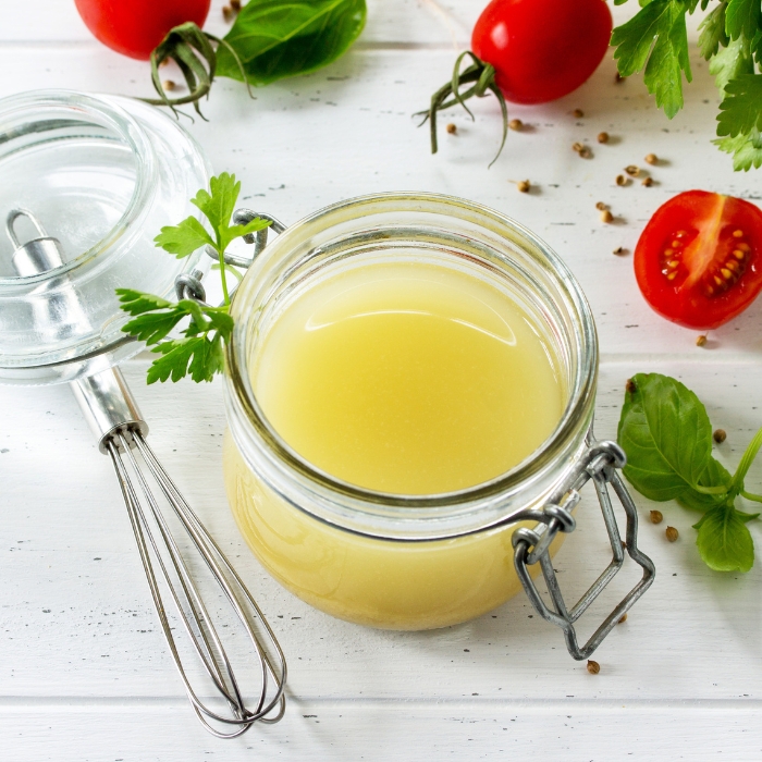 Homemade vinaigrette with mustard and olive oil in a jar on a table.
