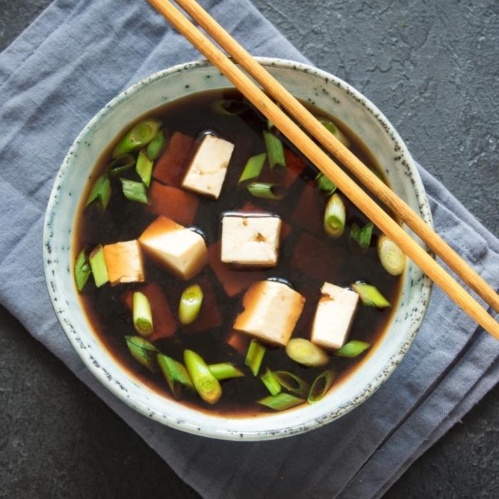 A bowl of miso soup with tofu and green onions.