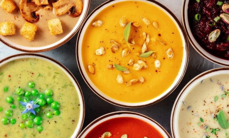 Variety of colorful vegan soups in bowls on a counter.