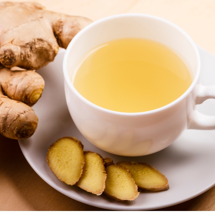 Mug of ginger tea with slices of fresh ginger.