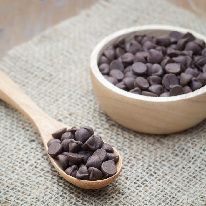 Chocolate chips in a wooden bowl and spoon.