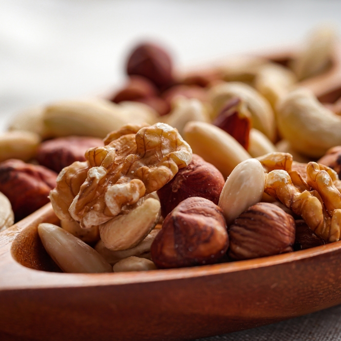 A variety of different nuts in a large wooden spoon.